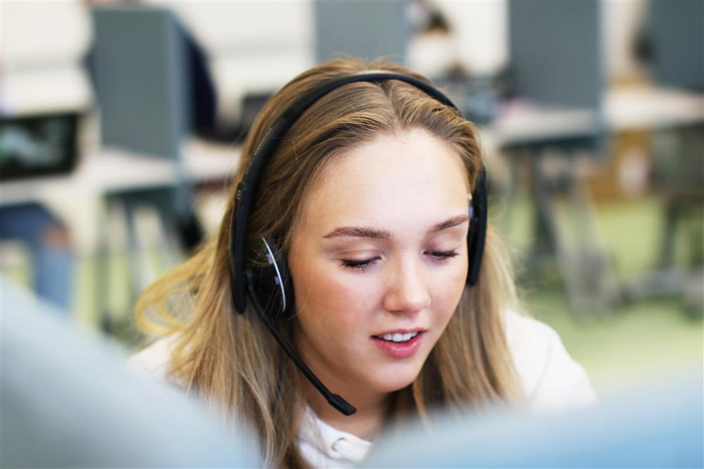 En kvinnelig elev som snakker i et headset med mikrofon.. - Klikk for stort bilde