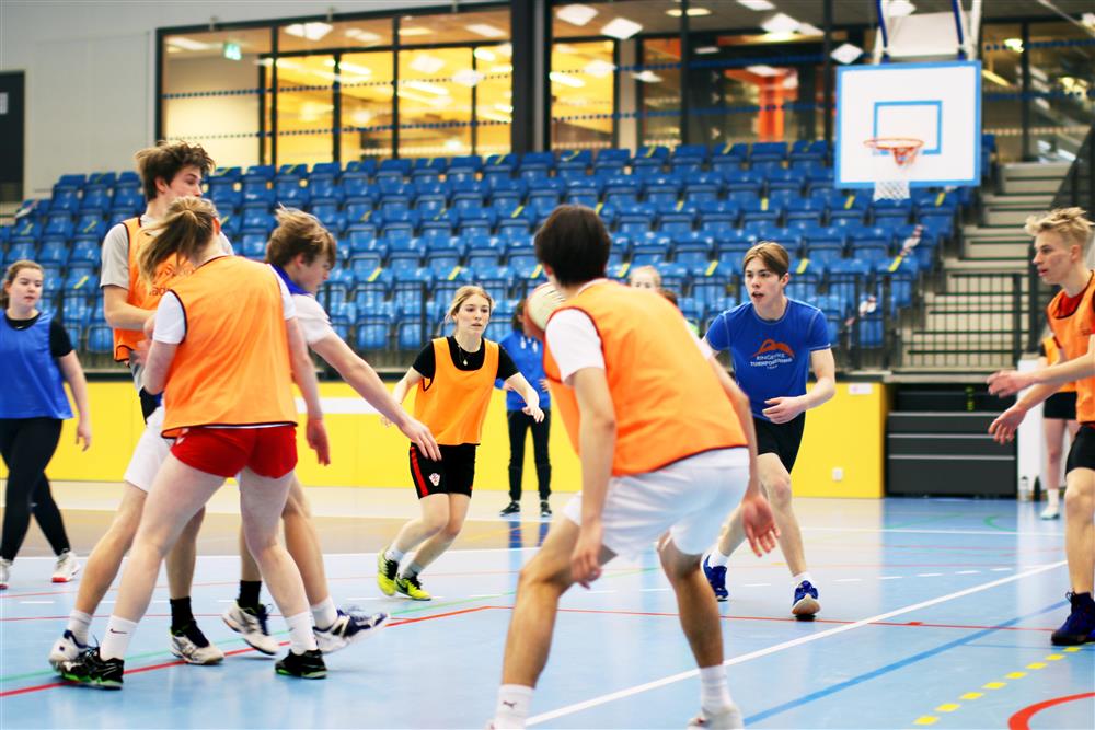 Ungdommer som spiller backetball i en idrettshall. - Klikk for stort bilde